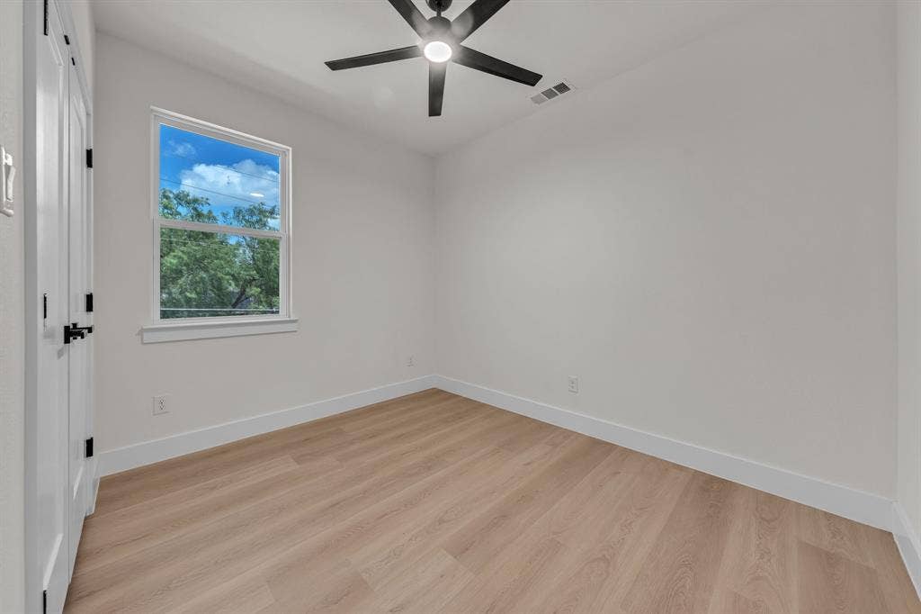 3639 Pueblo Street, Dallas, TX 75212 Neutral-toned room featuring wood-finish flooring, a matte black multi-blade ceiling fan with integrated lighting, and a double-door closet with black hardware