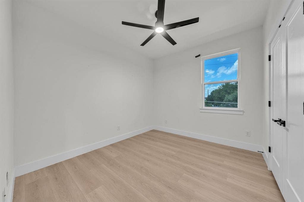 3639 Pueblo Street, Dallas, TX 75212 Interior space featuring wood-finish flooring, a matte black multi-blade ceiling fan with integrated lighting, a single-hung window, and a door with matte black hardware