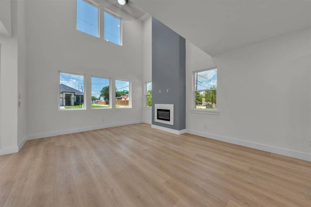 3639 Pueblo Street, Dallas, TX 75212 Two-story vaulted ceiling, wood-finish flooring, multi-pane windows, and a gas fireplace with a floor-to-ceiling surround