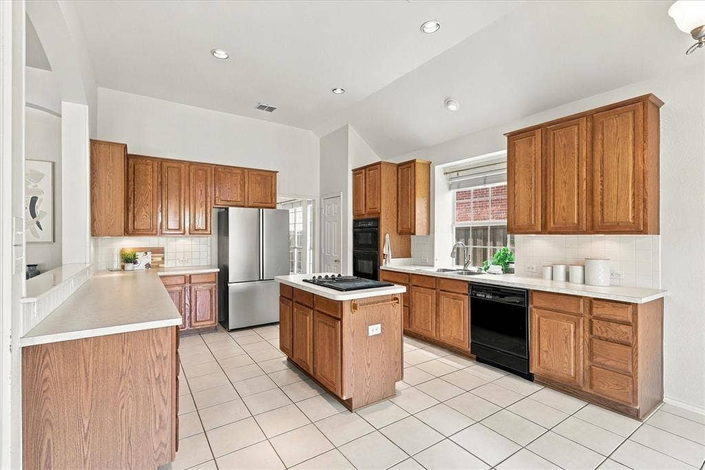 Kitchen featuring wood cabinetry, a central island with a built-in cooktop, and power to the island.