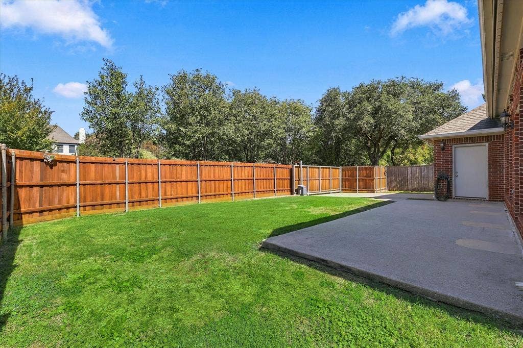 Fenced backyard featuring a manicured lawn and concrete patio.