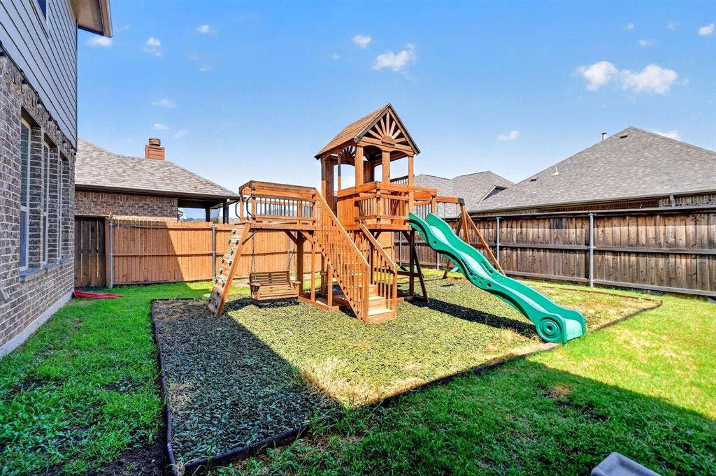 Backyard featuring a wood privacy fence, multi-level play structure, and an edged landscape border