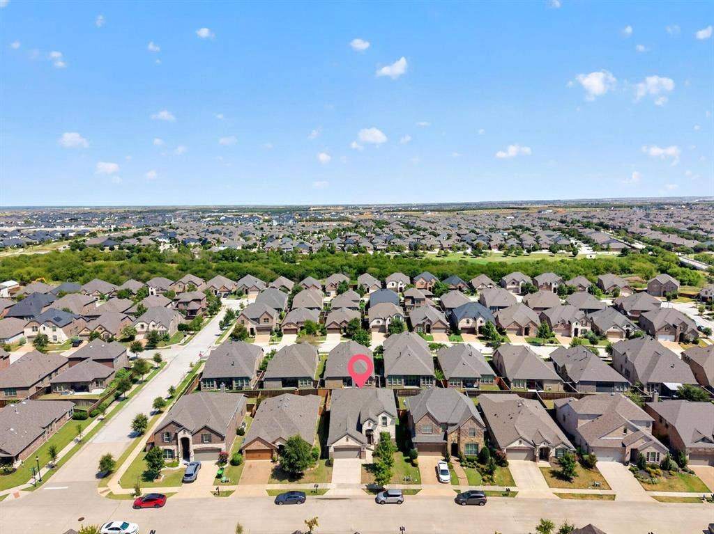 Aerial perspective of residential property featuring a multi-gabled roofline, brick and stone veneer exterior, attached two-car garage, and concrete driveway