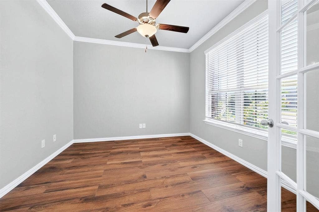 Room featuring wood-finish flooring, crown molding, a multi-pane glass door, and a ceiling fan with integrated lighting