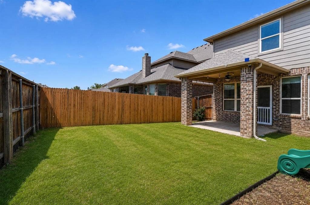 Backyard featuring a covered patio with masonry columns, horizontal lap siding, a fenced perimeter, and a grass lawn