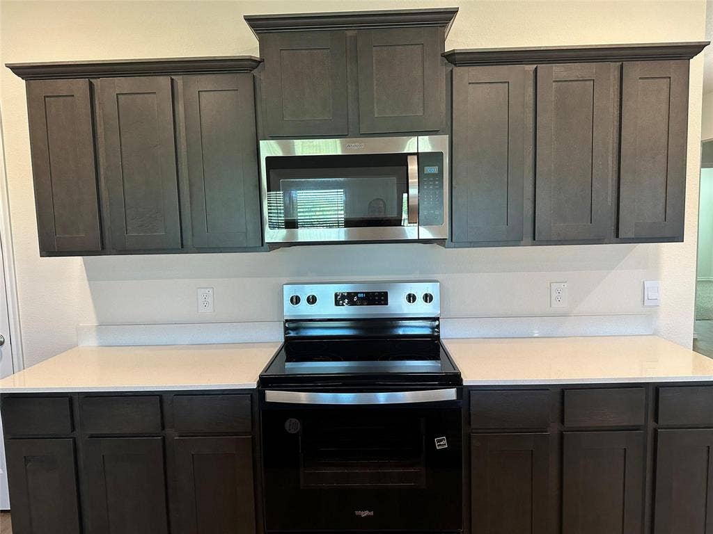 219 Greenshade, Caddo Mills, TX 75135 Kitchen with electric range oven, stainless steel microwave, and dark brown cabinets