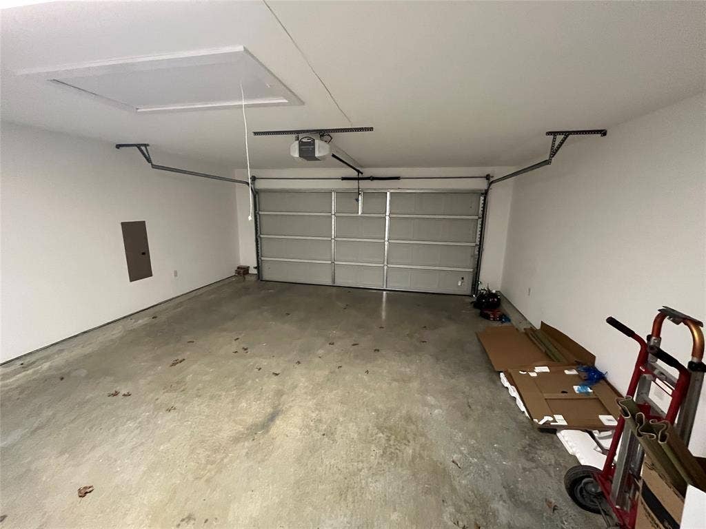 1104 Wake Drive, Richardson, TX 75081 Attached two-car garage featuring a sectional metal garage door, ceiling-mounted automatic door opener, and concrete flooring