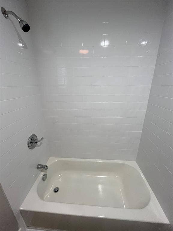 1104 Wake Drive, Richardson, TX 75081 Bathtub enclosure featuring white subway tile surround, polished chrome shower head, single-handle pressure-balance valve, and matching chrome tub spout