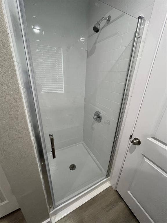 1104 Wake Drive, Richardson, TX 75081 Walk-in shower featuring white subway-style wall tiling, a glass door with a metal frame, a chrome shower head, and a chrome pressure-balance valve