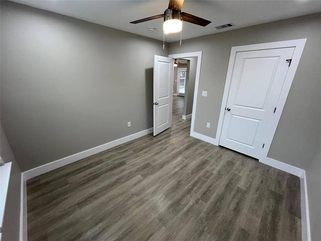 1104 Wake Drive, Richardson, TX 75081 Room featuring wood-finish flooring, neutral wall paint, white two-panel doors, and a ceiling-mounted light fixture with a fan
