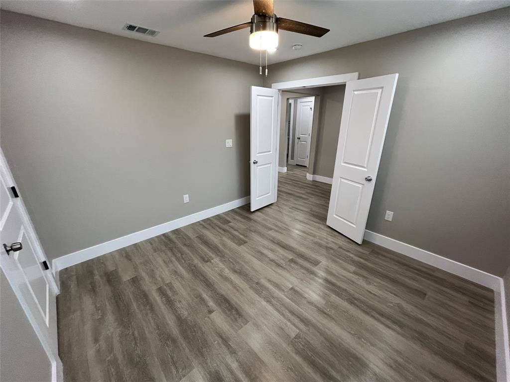 1104 Wake Drive, Richardson, TX 75081 Room featuring wood-finish flooring, two-panel interior doors, and a ceiling-mounted light fixture with a fan