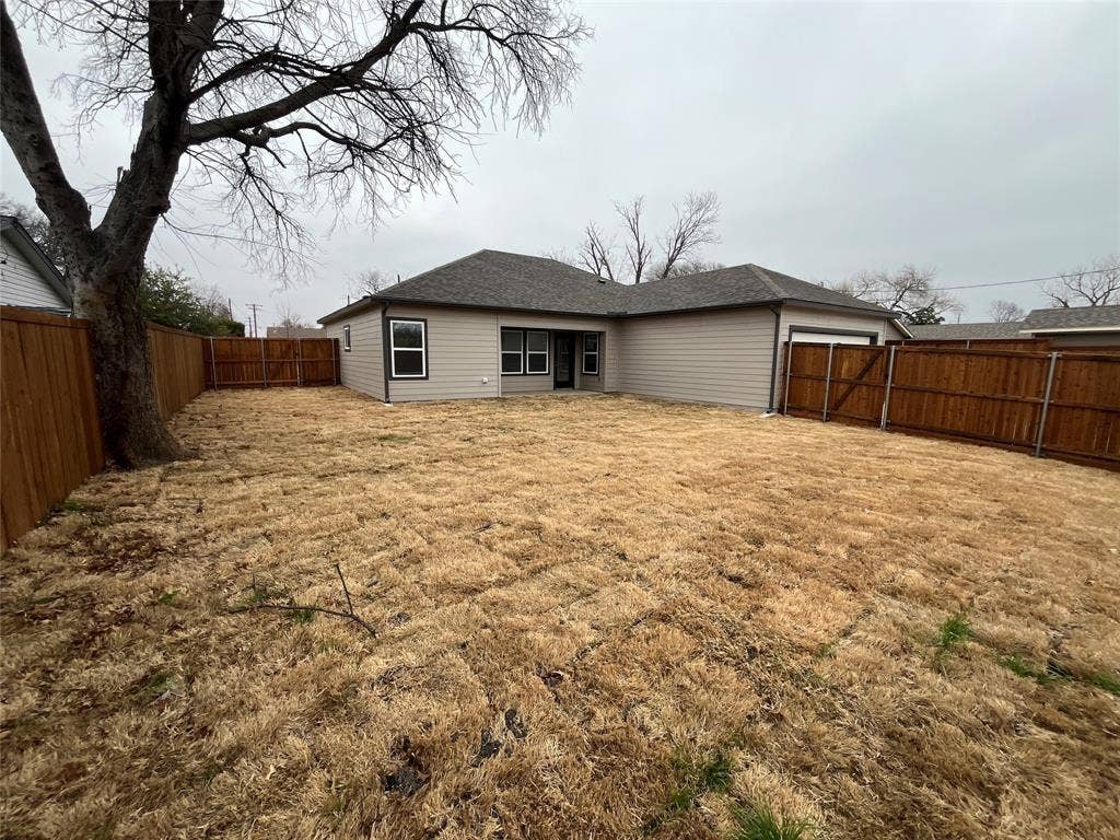 1104 Wake Drive, Richardson, TX 75081 Rear exterior featuring horizontal lap siding, a hip roof with asphalt shingles, and a fully enclosed wood privacy fence