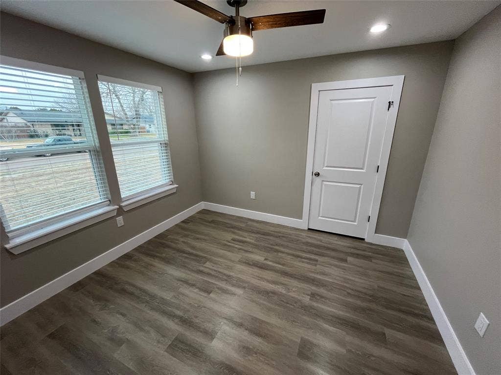 1104 Wake Drive, Richardson, TX 75081 Neutral-toned interior space featuring wood-finish flooring, dual windows with integrated blinds, a modern ceiling fan with light fixture, and a white two-panel door