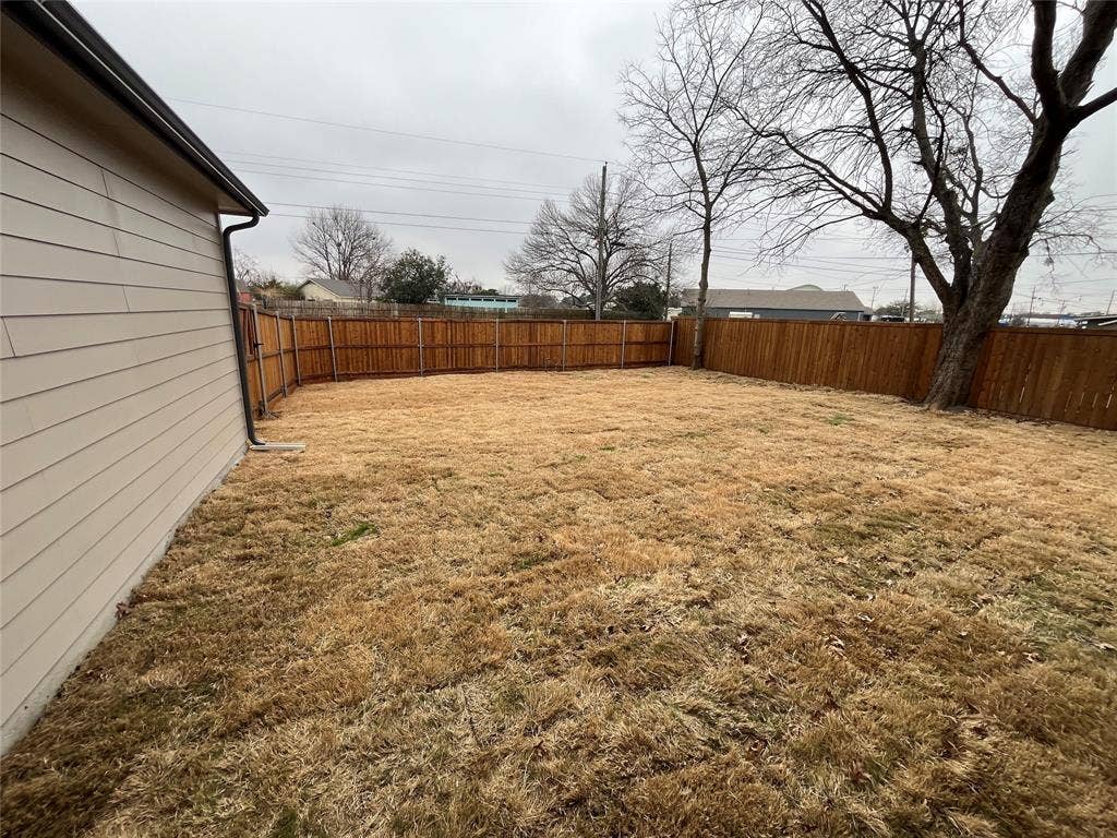 1104 Wake Drive, Richardson, TX 75081 Rear yard featuring horizontal siding, a wood privacy fence, and mature trees