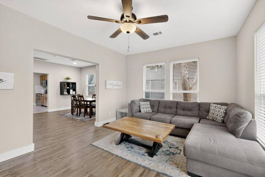 812 Centre Street, Dallas, TX 75208 Living area featuring wood-finish flooring, a ceiling fan with integrated lighting, and multiple windows with horizontal blinds