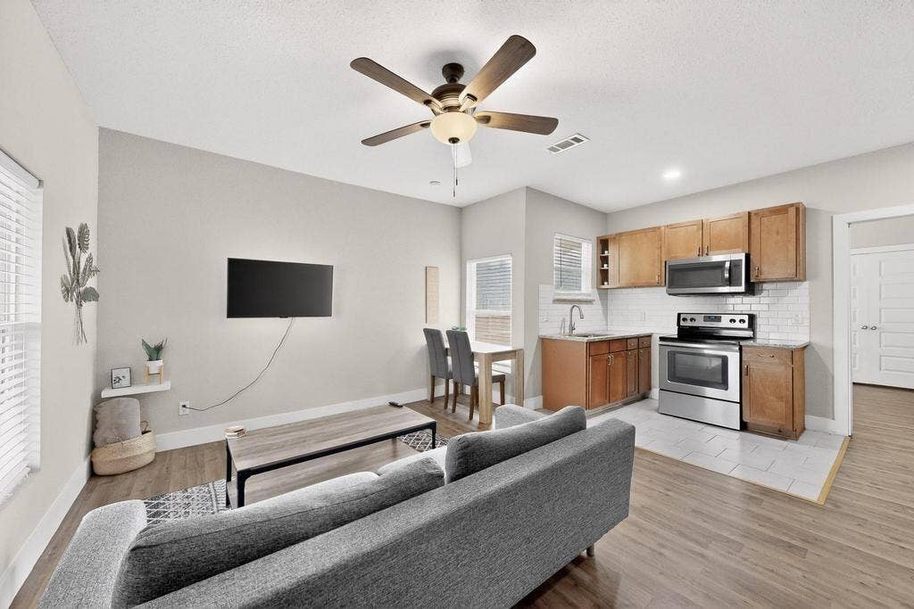 812 Centre Street, Dallas, TX 75208 Kitchen featuring wood-finish cabinetry, stainless steel appliances, and subway tile backsplash, complemented by wood-finish flooring and a multi-blade ceiling fan