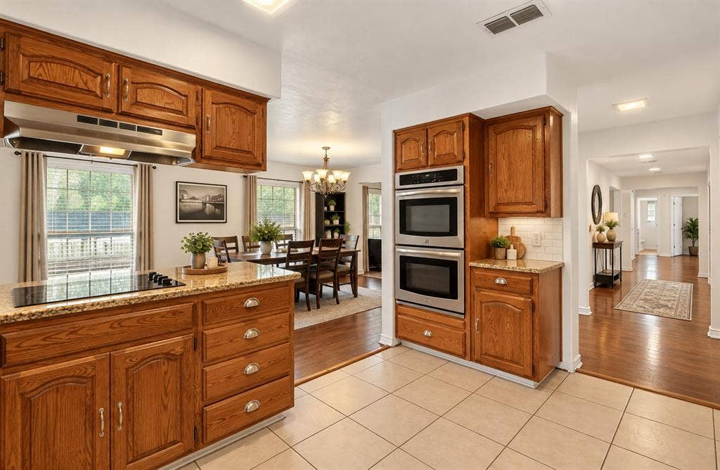 Kitchen featuring wood cabinetry, stone countertops, built-in double oven, glass cooktop, and tile flooring