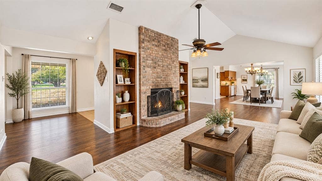 Vaulted ceilings, brick fireplace with built-in shelving, wood-finish flooring, and recessed lighting