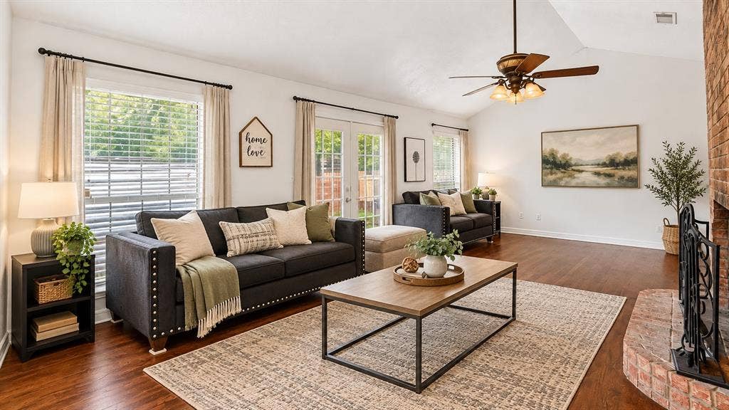 Living area featuring a vaulted ceiling, wood-finish flooring, brick fireplace hearth, and double glass doors