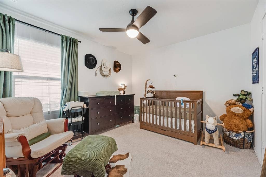 6742 Highlands Street, Princeton, TX 75407 Neutral-toned carpeting, matte black ceiling fan with integrated lighting, and window with built-in rod