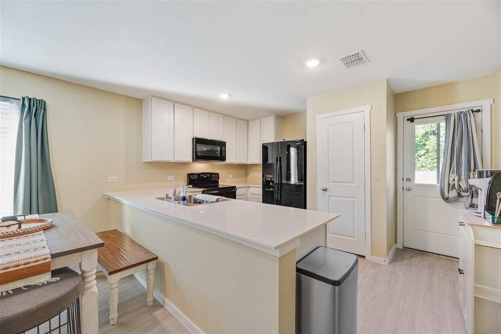 6742 Highlands Street, Princeton, TX 75407 Kitchen featuring white cabinetry, solid-surface countertops, recessed lighting, wood-finish flooring, and a glass-paneled exterior door