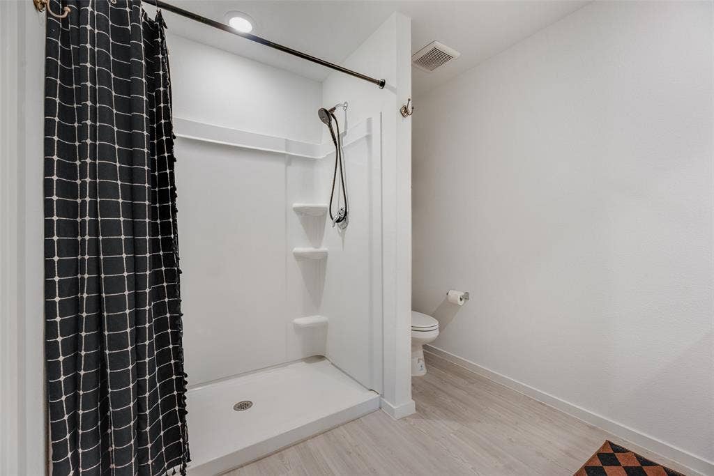 6742 Highlands Street, Princeton, TX 75407 Bathroom featuring a white molded shower surround with integrated shelving, a handheld shower fixture, recessed lighting, and wood-finish flooring