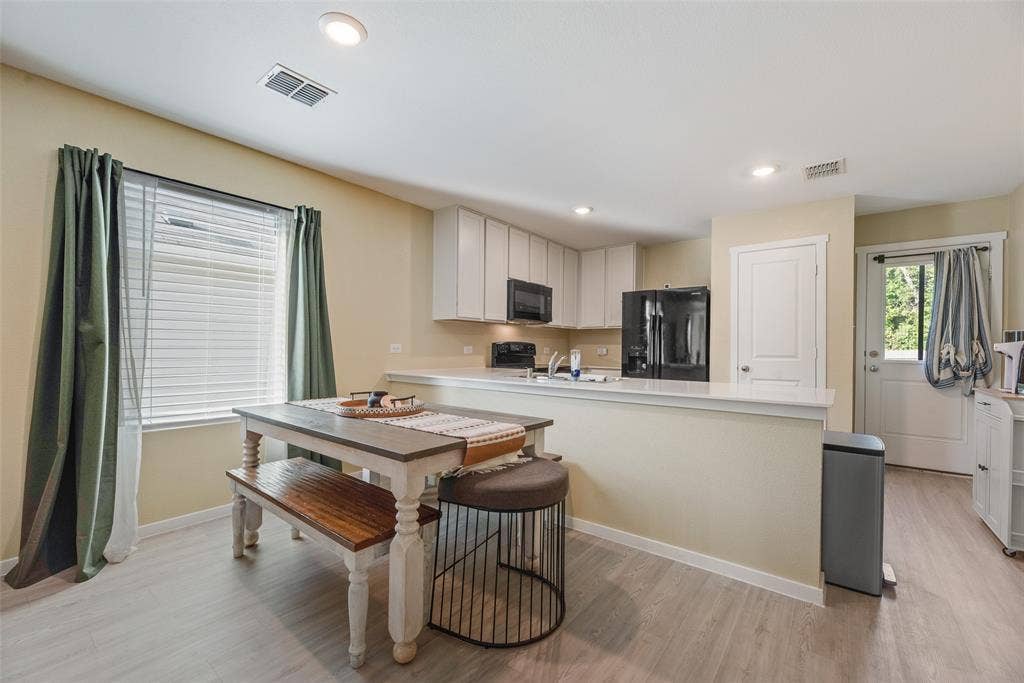6742 Highlands Street, Princeton, TX 75407 Kitchen featuring white cabinetry, a peninsula with a solid-surface countertop, recessed lighting, and wood-finish flooring