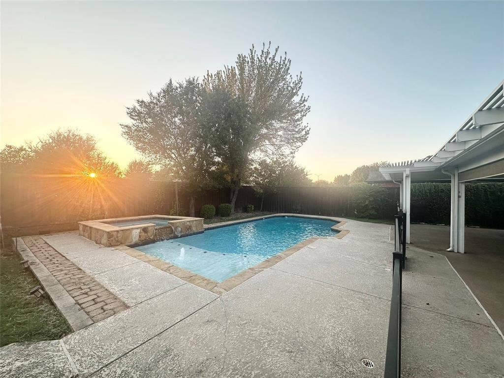 4327 Chasemoor Place, Frisco, TX 75035 In-ground swimming pool with an integrated elevated stone spa, concrete patio surround, and a covered pergola