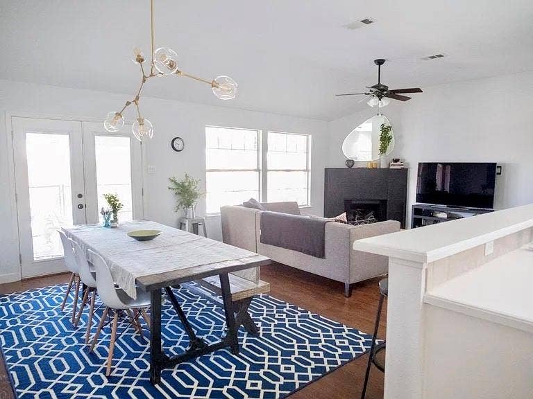 4327 Chasemoor Place, Frisco, TX 75035 Open-concept space featuring wood-finish flooring, a contemporary multi-arm pendant light fixture, a black floor-to-ceiling fireplace surround, and double-glass paneled doors