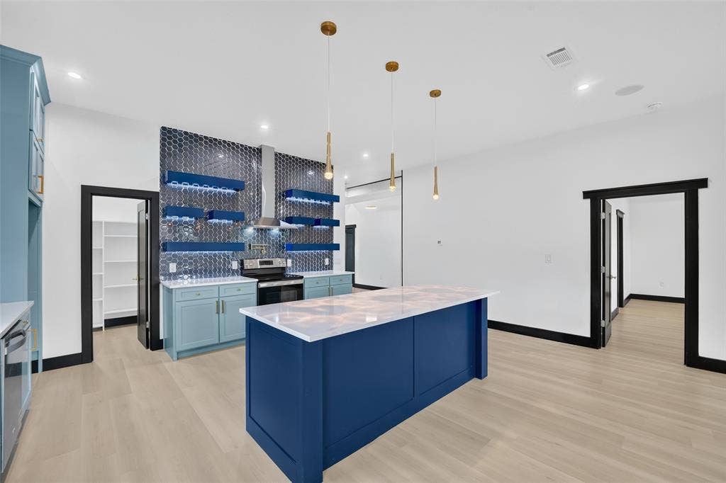 601 Melody Circle, Kaufman, TX 75142 Kitchen featuring a central island with a solid surface countertop, honeycomb-patterned tile backsplash, integrated floating shelves with recessed lighting, and wood-finish flooring