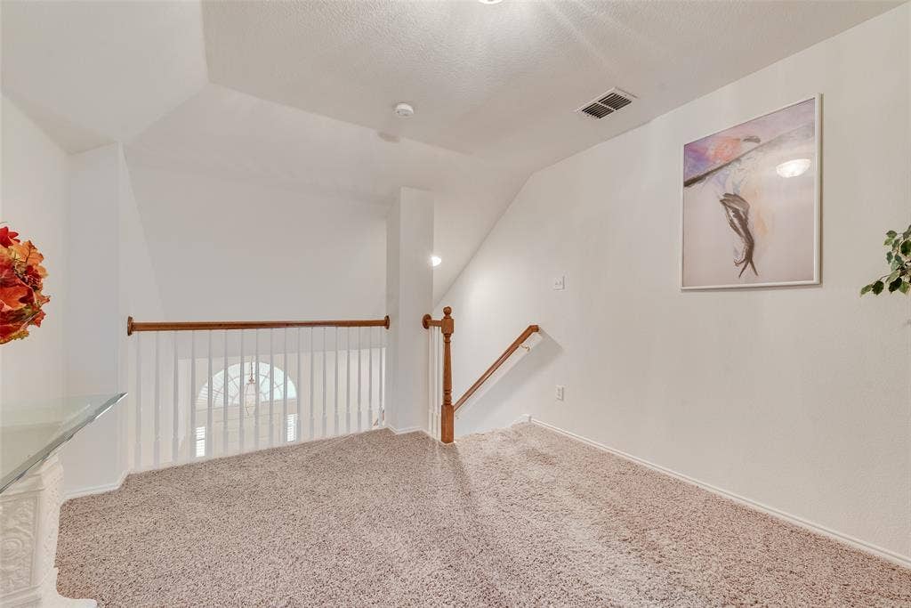 148 Oakbluff Drive, Murphy, TX 75094 Neutral wall-to-wall carpeting, wood-finish balustrade, white spindle railing, and vaulted ceilings