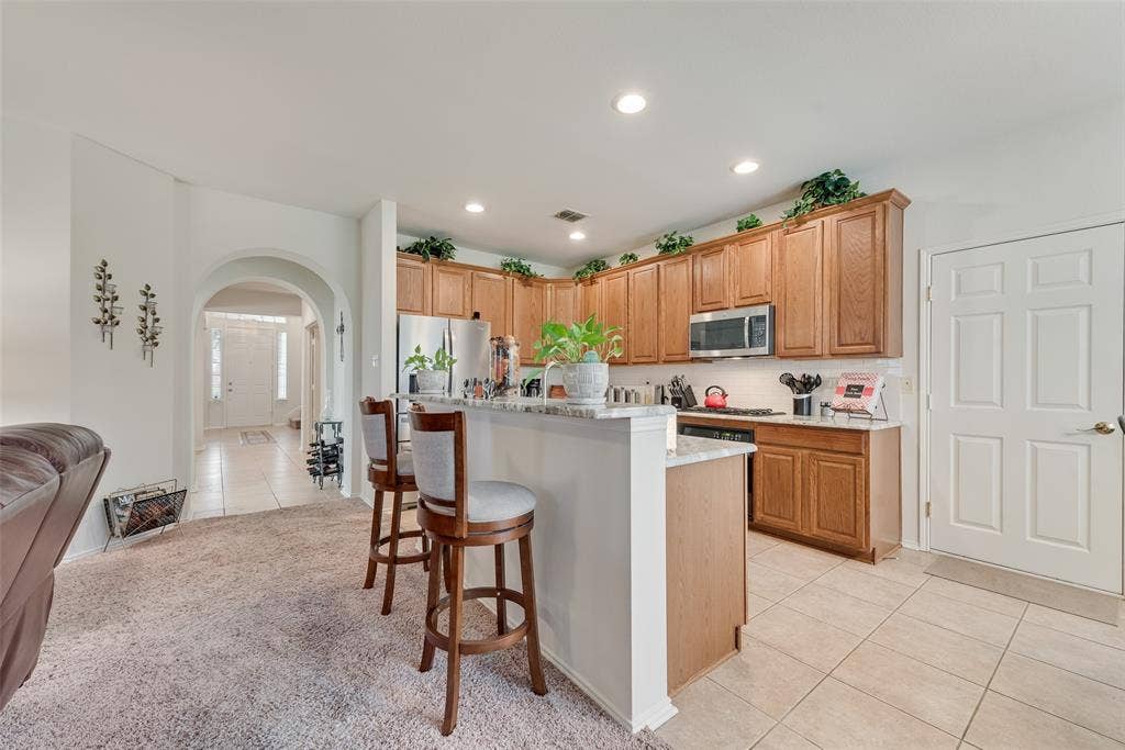 148 Oakbluff Drive, Murphy, TX 75094 Kitchen featuring wood cabinetry, stone-finish countertops, stainless steel appliances, a breakfast bar, and recessed lighting