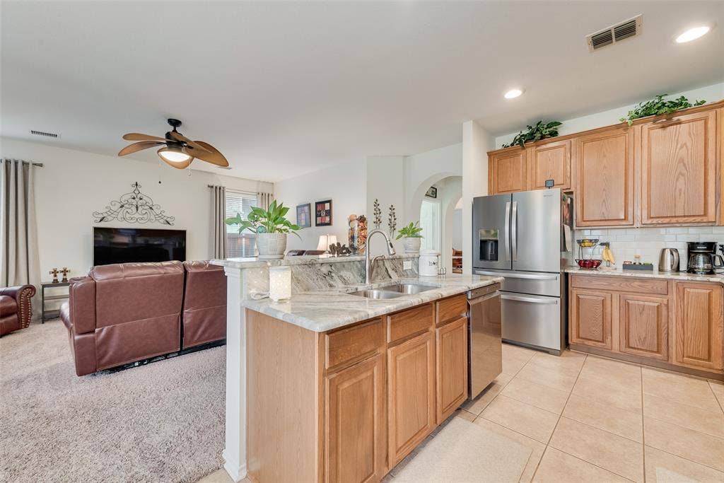 148 Oakbluff Drive, Murphy, TX 75094 Kitchen featuring wood cabinetry, stone countertops, a stainless steel refrigerator, tile flooring, and a ceiling fan