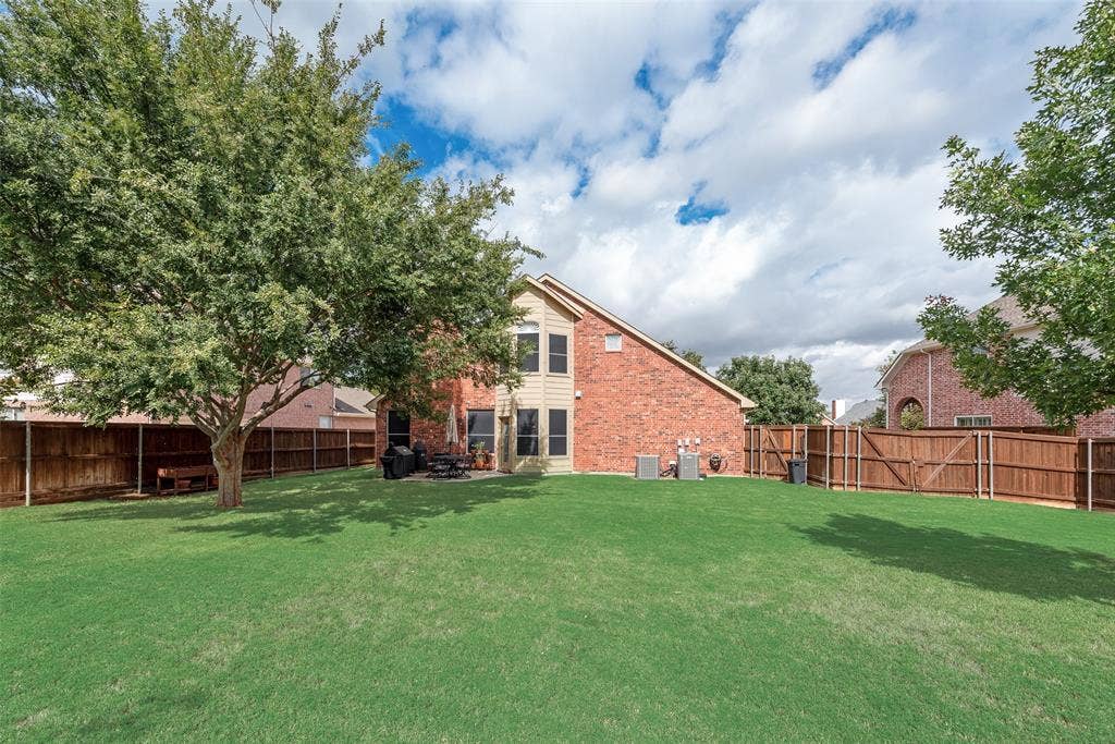148 Oakbluff Drive, Murphy, TX 75094 Fenced backyard featuring a manicured lawn, mature trees, and a concrete patio