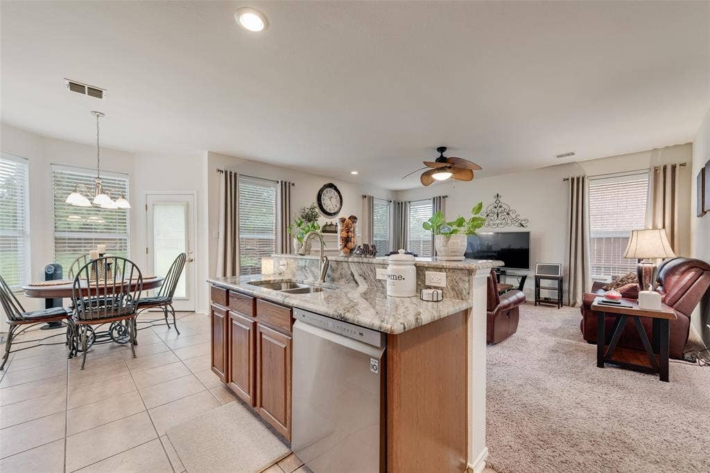 148 Oakbluff Drive, Murphy, TX 75094 Kitchen island with stone countertop, stainless steel dishwasher, wood-finish cabinetry, tile flooring, and ceiling fan