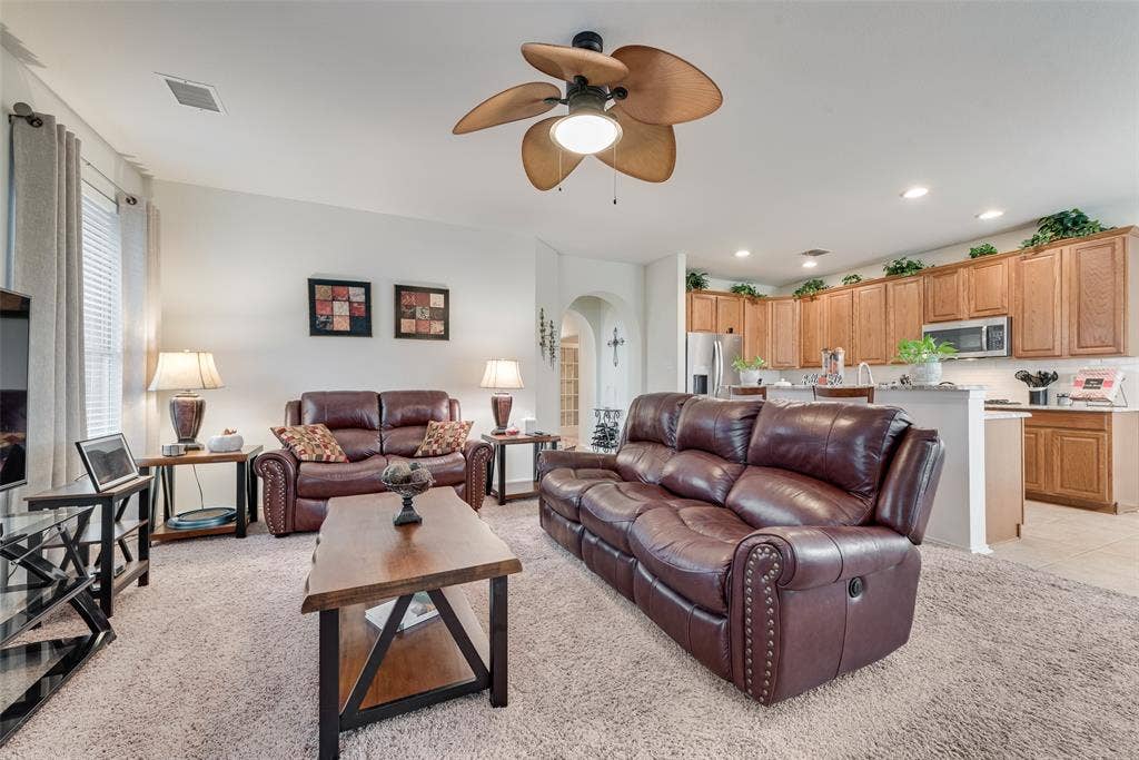 148 Oakbluff Drive, Murphy, TX 75094 Open-concept living space featuring a palm-style ceiling fan, recessed lighting, arched entryway, and kitchen cabinetry with stainless steel appliances