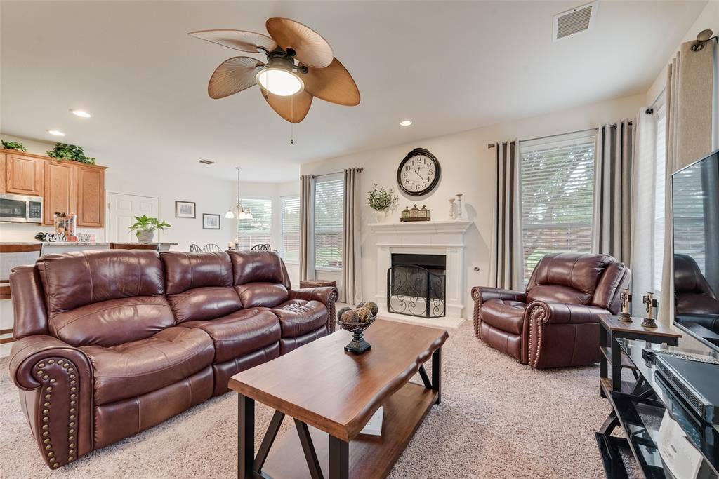 148 Oakbluff Drive, Murphy, TX 75094 Living area featuring a fireplace with a white mantel, ceiling fan with palm-style blades, recessed lighting, and multiple windows
