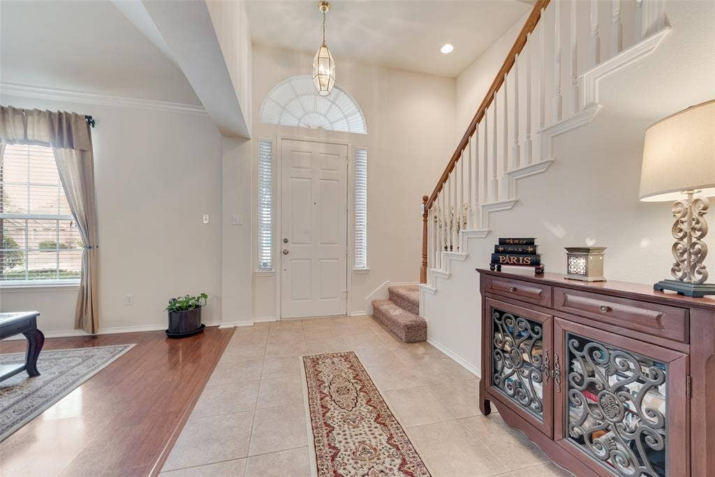 148 Oakbluff Drive, Murphy, TX 75094 Foyer featuring tile flooring, a staircase with white balusters and wood-finish handrail, and an entryway door with arched transom window and sidelights