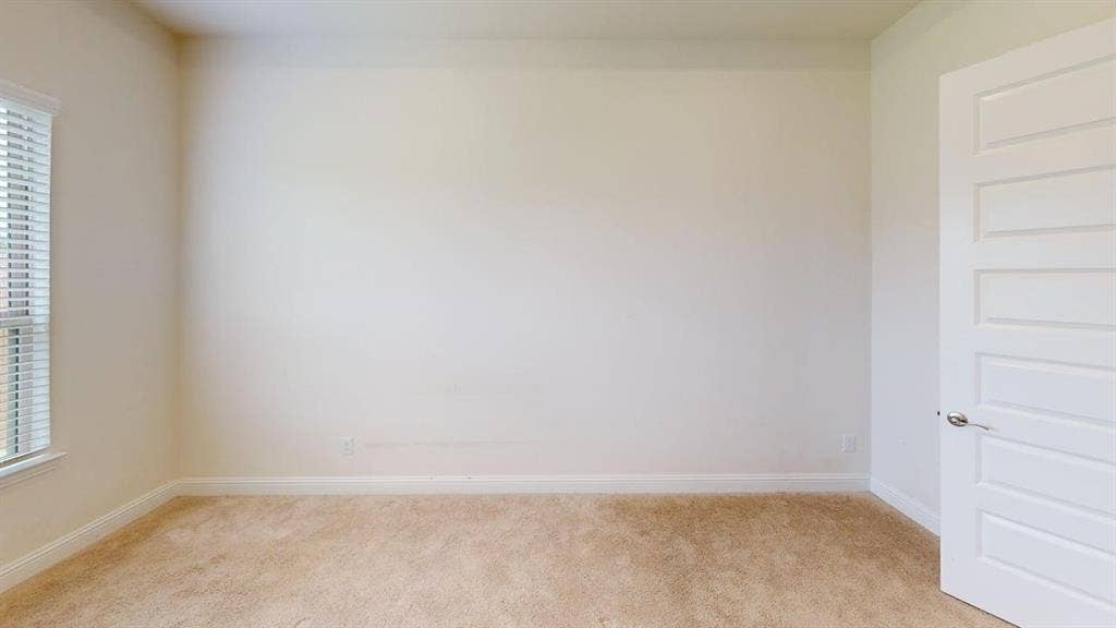333 Elk Drive, Fate, TX 75189 Interior space featuring neutral-toned carpeting, five-panel interior door with brushed nickel hardware, and window with horizontal blinds