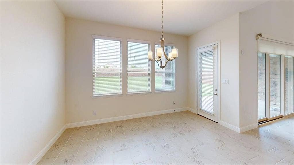 333 Elk Drive, Fate, TX 75189 Neutral-toned tile flooring, three large windows with integrated blinds, a metal chandelier, and glass-paneled exterior doors