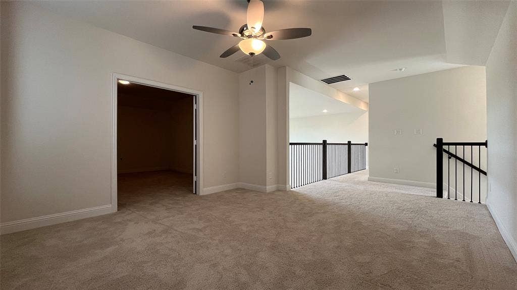 333 Elk Drive, Fate, TX 75189 Neutral-toned interior space featuring carpeting, a ceiling fan with integrated lighting, recessed lighting, and a metal balustrade staircase railing