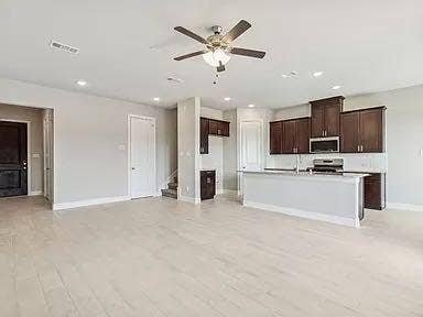 333 Elk Drive, Fate, TX 75189 Open-concept kitchen featuring dark wood cabinetry, a breakfast bar, recessed lighting, and light-toned flooring throughout