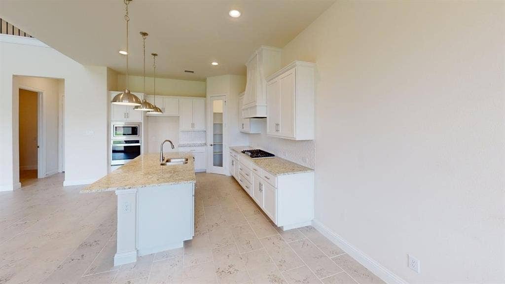 333 Elk Drive, Fate, TX 75189 Kitchen featuring white cabinetry, stone-surface countertops, center island with undermount sink, built-in double wall oven, and pendant lighting