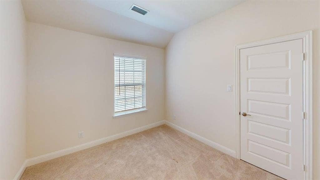 333 Elk Drive, Fate, TX 75189 Neutral interior space featuring vaulted ceilings, neutral-toned wall-to-wall carpeting, a multi-panel interior door, and a single-hung window with blinds