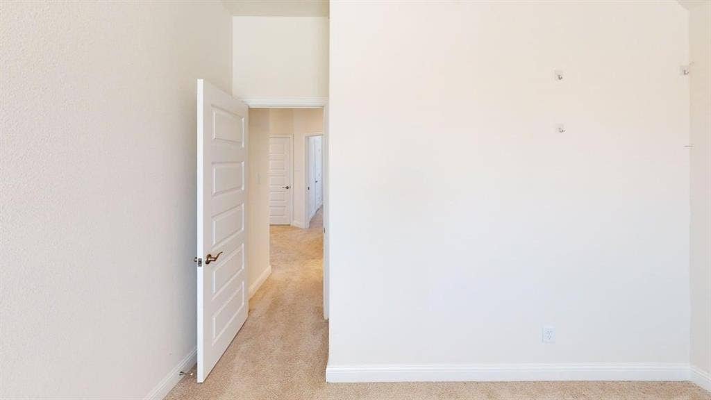 333 Elk Drive, Fate, TX 75189 Five-panel interior door with a brushed metallic lever handle, neutral wall-to-wall carpeting, and crisp white wall finishes