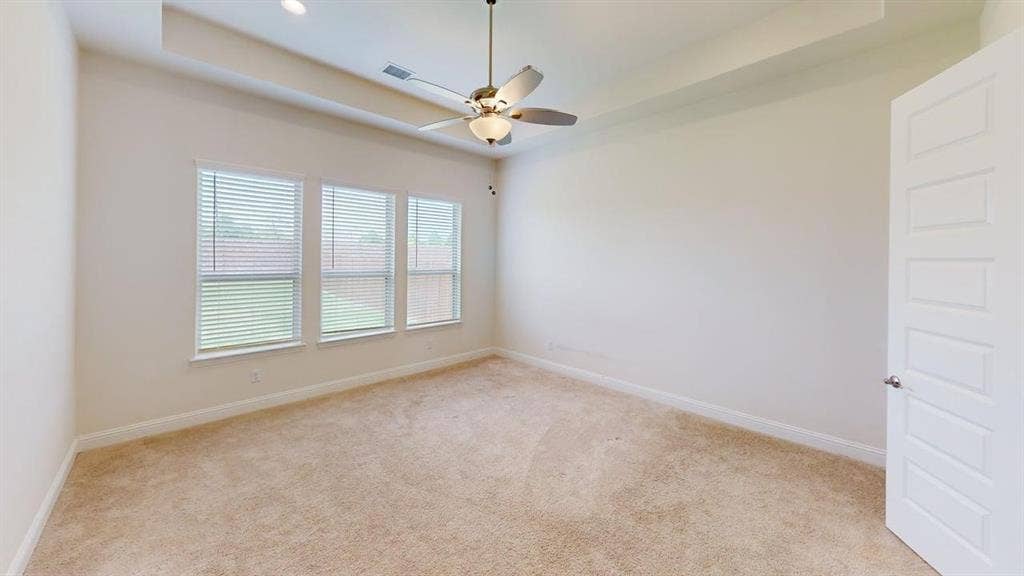 333 Elk Drive, Fate, TX 75189 Room featuring a tray ceiling, ceiling fan with light kit, neutral carpeting, and triple-window configuration with horizontal blinds