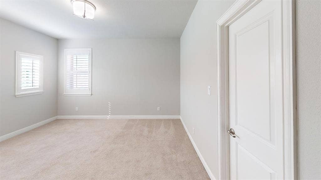 7005 Golf Club Drive, McKinney, TX 75070 Neutral interior space featuring carpeted flooring, two windows with plantation shutters, a flush-mount light fixture, and a white panel door