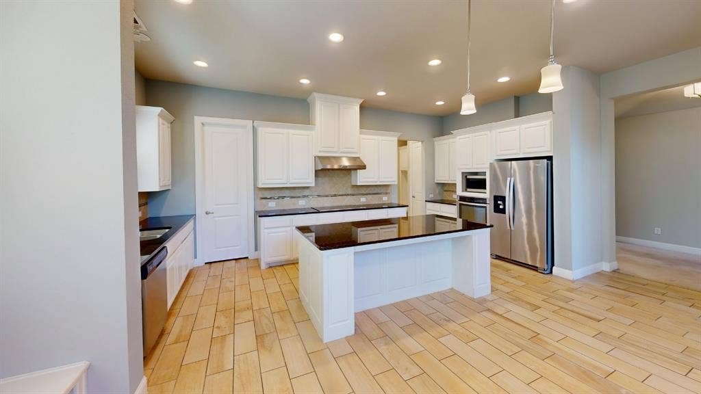 7005 Golf Club Drive, McKinney, TX 75070 Kitchen featuring white cabinetry, center island with dark countertops, stainless steel appliances, recessed ceiling lighting, and wood-finish tile flooring