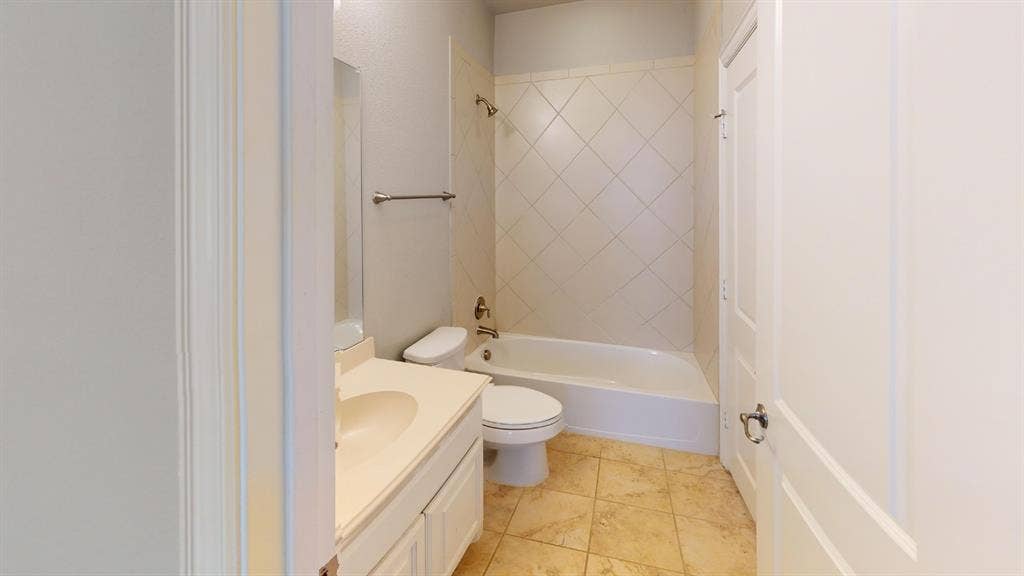 7005 Golf Club Drive, McKinney, TX 75070 Bathroom featuring a vanity with integrated sink, tile flooring, and a tub with diamond-pattern tile surround