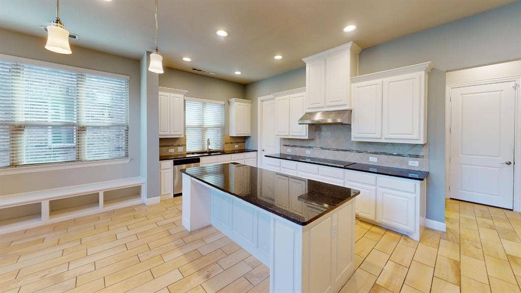 7005 Golf Club Drive, McKinney, TX 75070 Kitchen featuring an island with stone countertops, white cabinetry, tile backsplash, wood-finish flooring, and recessed lighting